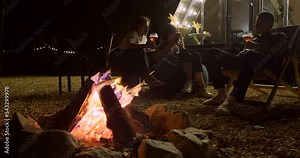 Campfire with group of friends on background on backyard in night party. Close-up view of bonfire