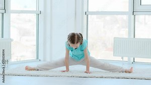 Cute little girl performing gymnastics in bright room
