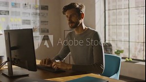 Creative Designer Sitting at His Desk in Office Studio Working on a Desktop Computer with Smartphone Software Development Application on Screen. Web, App Developer. 360 Degree Tracking Arc Shot