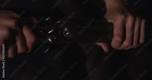 Close up of a double-barreled shotgun being opened and empty shells being pulled out of the weapon. The weapon gets put down on the floor