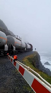 A static ultra wide 8K shot captures a massive freight train moving along a foggy cliffside railway | Alaska Northern