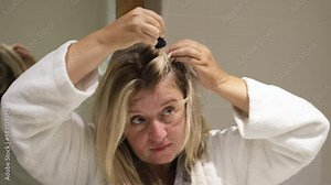Woman applies oil to her hair with pipette. Beauty caring for scalp and hair.
