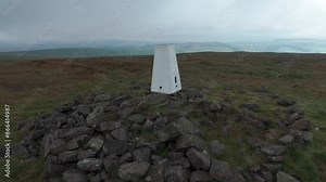 Rotating aerial shot of Trigonometrical point or Triangulation point at the summit of Titterstone Clee hill in Shropshire, UK.
