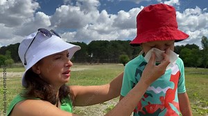 Child with pollen allergy mom sneezing and blowing little boy nose because of seasonal allergy