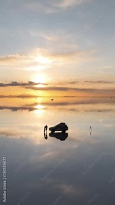 Salar de Uyuni in Bolivia during sunset. Aerial image taken with a drone. Uyuni Salt Flats. Altiplano, Bolivia. Rainy Season. Tunupa Volcano. Clouds Reflection on Water in Lake Surface. Vertical video