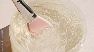 Transparent liquid gel background, clear serum texture. Motion of the beauty skincare product sample with bubbles, makeup brush. Organic cosmetics, medicine. Macro Shot. High quality 4k footage.