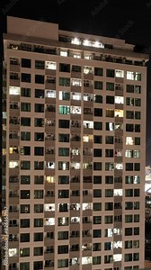 Time-lapse Shoot of High-rise Residential House or Apartment at Evening Time in City Downtown. Windows Lights Turn on and Turn Off, Vertical Orientation
