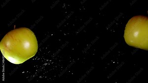 Two juicy tasty apples collide with each other and spin on a black background in slow motion. High quality 4k footage