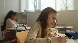 Schoolgirl learning in classroom. cheerful pupil sitting at desk during lesson Free Stock Video Footage