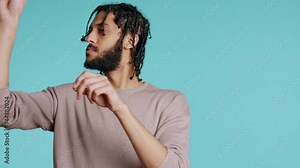 middle eastern conductor performing classical music concert following imaginary sheet music. Man doing delicate swinging hand motions, pretending to conduct orchestra, studio background, camera B