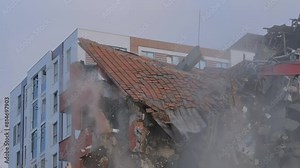 Slow motion: demolition of building, moment of roof collapse: excavator with hydraulic crusher is tearing down the old typical Turkish multi-storey apartment, residential building in Istanbul, Turkey