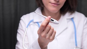 Female doctor showing electronic thermometer. measuring body temperature
