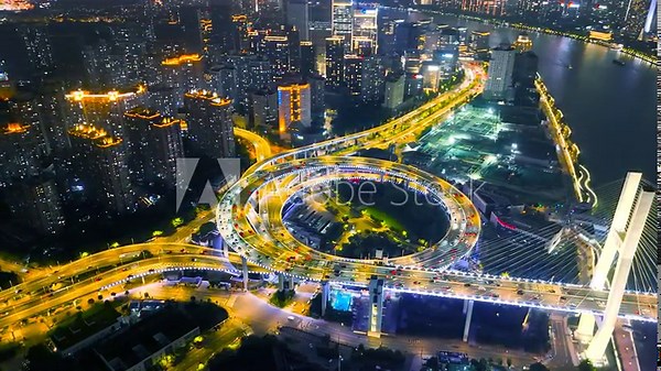 Aerial of the illuminated Nanpu Bridge interchange with heavy night traffic, surrounded by high-rise buildings and the Huangpu River, Shanghai, China.