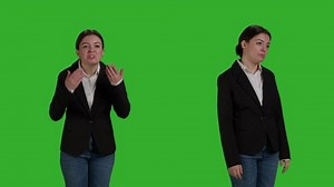 Young angry businesswoman acting negative and furious on camera, standing over greenscreen backdrop. Female employee being in conflict and expressing disagreement or disapproval in studio.