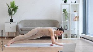 Beautiful calm yogini in beige activewear improving body strength while holding Side Plank Pose with lifted leg. Healthy senior female practising modern yoga with Vasisthasana exercise at home.