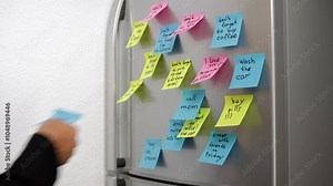 Businessman Checking Off Colorful Post-It Notes on Refrigerator. Notes Reminders For Various Tasks and Appointments