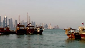 An Arab dhow boat at sea against the backdrop of the modern city of Doha, Qatar
