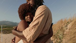 A couple tightly embracing each other on a secluded beach with the warm sunset light reflecting a mood of peacefulness and love.