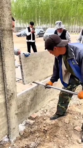 Workers install concrete panels for building walls using proper tools and neat techniques