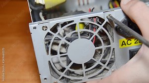 Power supply repair. Computer technician disassembles a computer. master removes dusty cooler. unscrews the fastening screw