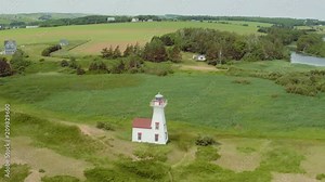 Drone rotates around lighthouse on ocean shore in Prince Edward Island