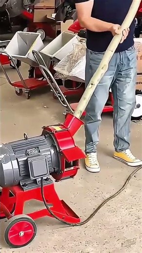 Shredding a long tree branch into wood chips using a powerful electric wood chipper machine