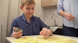 The boy cuts circles from the rolled out dough. Homemade food. Close-up
