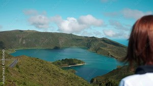 Woman looking to the landscape nature of the Fire Lagoon (Lagoa do Fogo) background enjoying vacation travel adventure in the Island of São Miguel in the Azores.