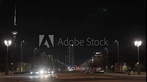 Night shot of Berlin Karl-Marx-Allee with TV tower, Park Inn, Haus des Lehrers. A car turns on the boulevard, an ambulance has its blue light on in the background.