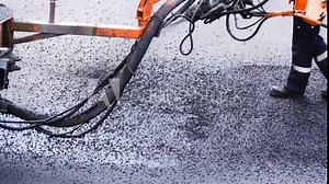 Road worker sprays hot bitumen to cover holes or cracks in the asphalt road.