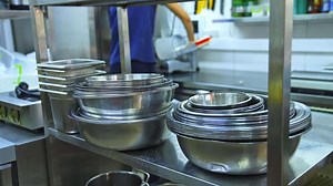 An industrial kitchen utensils close up. Stainless steel bowl and plastic container at commercial kitchen.
