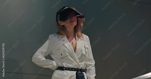 Portrait of young smiling woman wearing white designer jacket and fashionable face shield. Fashion model in colorful flashing ultra violet neon light. Happy smile on positive female face. Footage 4K
