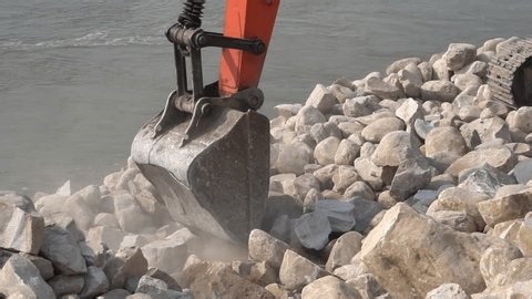 clip-3997293269-excavator-bucket-moving-large-stones-river-construction