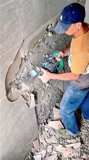 A worker is removing old tile and mortar using a rotary hammer