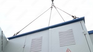 Bottom view of a transformer box that rotates in the air suspended on a construction crane Stock Video