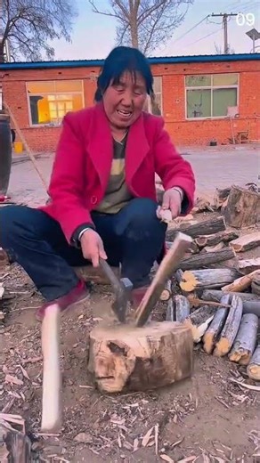 Person in red jacket splitting wood with axe