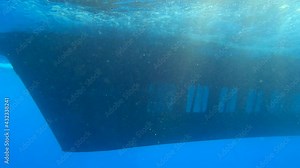 Aquascope submarine with tourists on board swim in blue water (Underwater view). Yellow submarine floats in blue water, people look at the underwater world through eluminators (4K-60pfs)