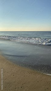 Ebb and flow of the North Sea coast, movement of cold water with white foam on the amazing sunset