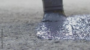 Close up detail of worker with paintbrush covering concrete floor with protection primer, coating, bitumen, paint.