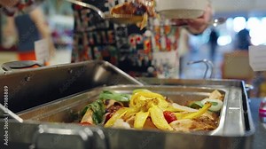 A woman puts food on his plate at a buffet table. All inclusive service. Self Service Catering Buffet. Female hand, woman takes vegan food from heated trays in restaurant, hotel. Close-up.