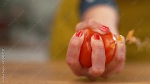 SLOW MOTION, MACRO, DOF: Organic tomato explodes in a female chef's hand as she squeezes it while making a sauce. Unrecognizable woman squeezes a ripe tomato and water and seeds come bursting out.
