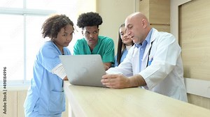 A medical professor gives advice on patient examinations to medical students practicing in an international medical hospital.