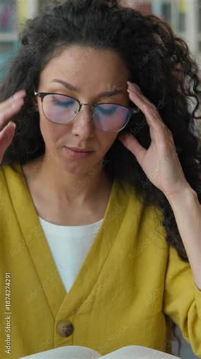 Stressed frustrated Hispanic Arabian woman student studying burnout in library university female girl preparing exam headache painful reading book suffering unwell health textbook college high school