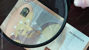 Examination of a fifty euro banknote under a magnifying glass. Concept, finance, banking, economy.