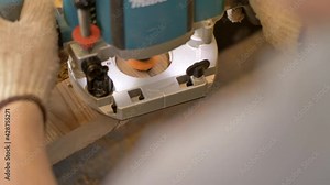 Carpenter using plunge router with electrical brake and twin LED light for fine precision work on thermo pine plank. Thermowood preparation for wood construction.