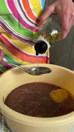 Vertical side view video: oil is gradually added with a large spoon into a bowl with liver and eggs, cooking process