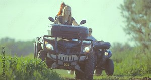 Girl driving ATV rides in the field on the road