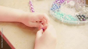 Preschool girl engaged in arts and crafts activity, DIY craft project, making personalized bracelet with colorful beads, fine motor skills, promoting creativity and self-expression
