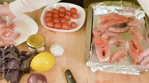 Close-up of female hands spread on a baking tray for roasting seafood