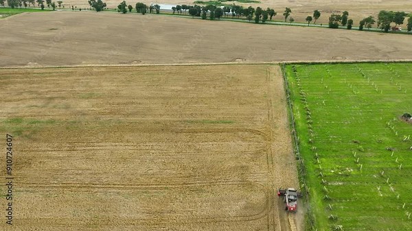 Top view of a red combine harvester at work in a field, emphasizing the scale of the field and the efficiency of modern agricultural practices